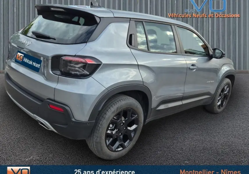 Jeep Avenger gris foncé vu en 3/4 arrière côté droit, avec jantes noires et feux arrière fumés.