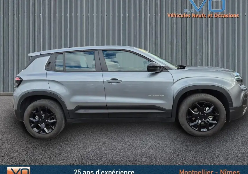 Profil côté gauche d'un Jeep Avenger gris foncé 2024 avec jantes noires et lignes épurées visibles.