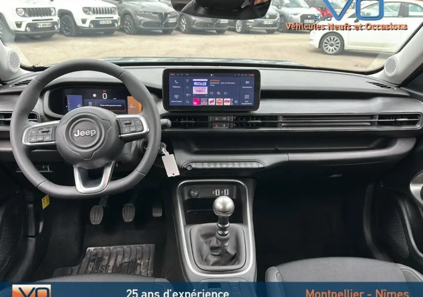 Intérieur du Jeep Avenger 2024 gris foncé, vue frontale sur le tableau de bord avec écran tactile et boîte manuelle.