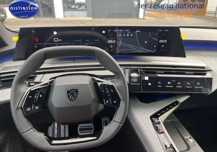 Vue intérieure centrée sur le volant cuir gris et le tableau de bord numérique large du Peugeot 3008 gris titane 2025.