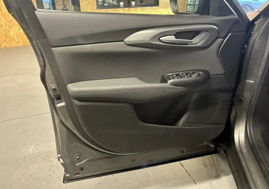 Vue intérieure côté gauche de la porte avant gris foncé de l'Alfa Romeo Tonale 1.3 PHEV avec commandes électriques et garniture noire.