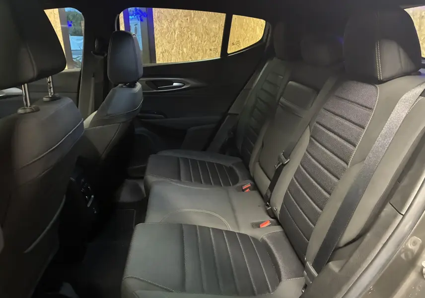 Vue intérieure arrière côté droit de l'Alfa Romeo Tonale 1.3 PHEV 280 BVA TI 2023 avec sièges en cuir noir et ceintures de sécurité visibles.