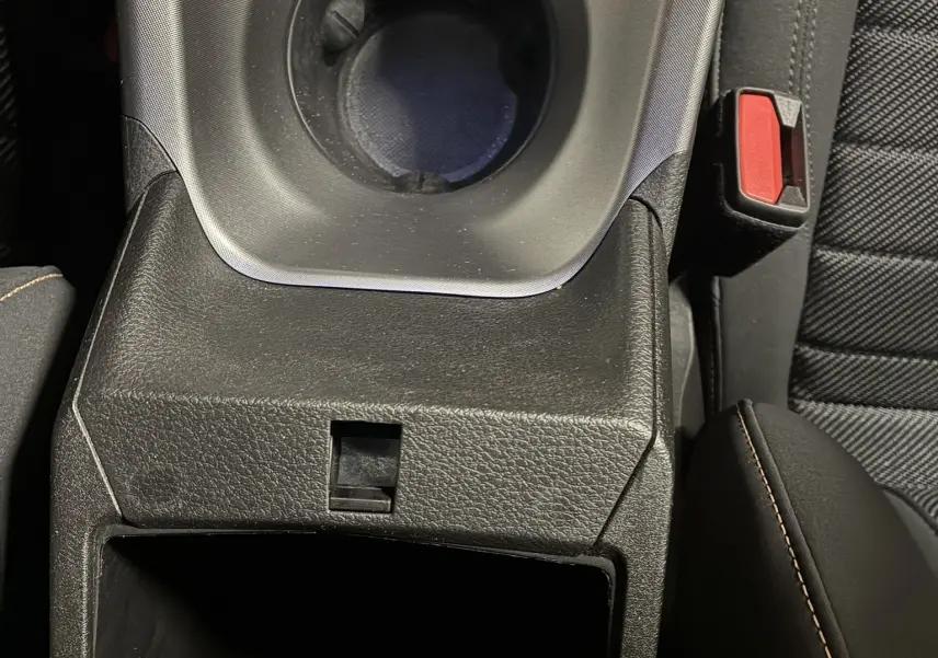 Gros plan sur la console centrale noire de l'Alfa Romeo Tonale 1.3 PHEV avec porte-gobelets et accoudoir en cuir noir.