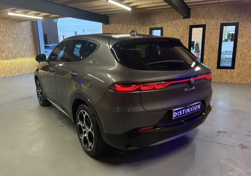 Vue 3/4 arrière droite de l'Alfa Romeo Tonale gris foncé 2023 avec feux arrière LED distinctifs dans un garage.