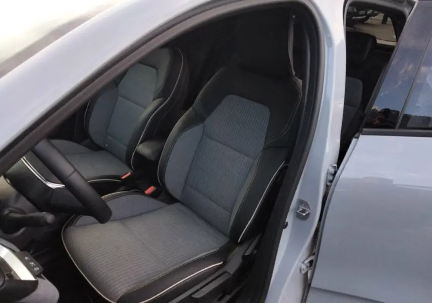 Vue intérieure côté conducteur de la Renault Clio gris rafale 2025, montrant les sièges avant en tissu et cuir noir.