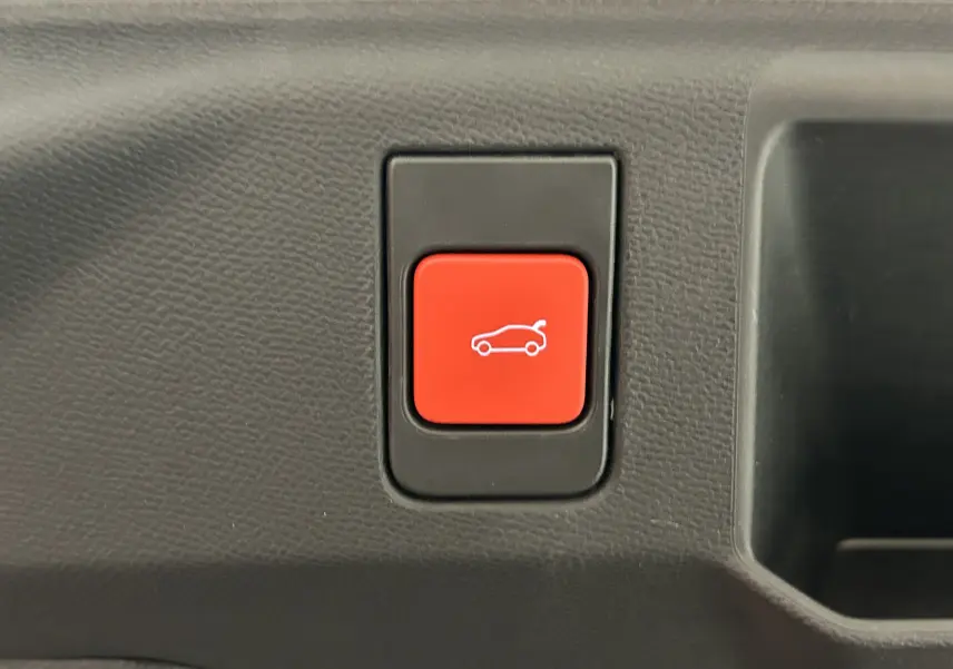 Bouton rouge de commande électrique du hayon sur tableau de bord intérieur du Peugeot 5008 gris titane 2025.
