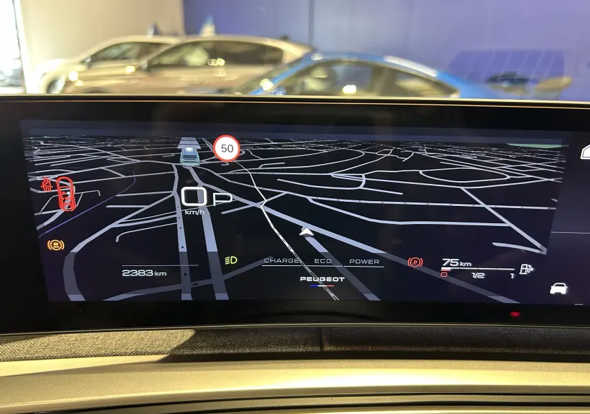 Affichage numérique du tableau de bord du Peugeot 5008 Hybrid gris titane, montrant la navigation et les indicateurs de conduite.