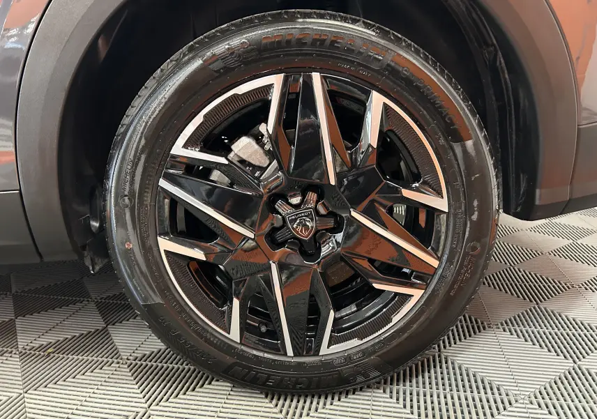 Gros plan sur la jante noire et argentée du côté gauche d’un Peugeot 5008 gris titane avec pneu Michelin.