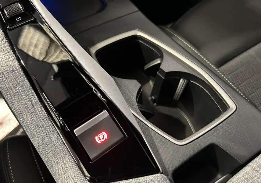 Gros plan sur la console centrale noire et grise avec porte-gobelets du Peugeot 5008 Hybrid 2025.