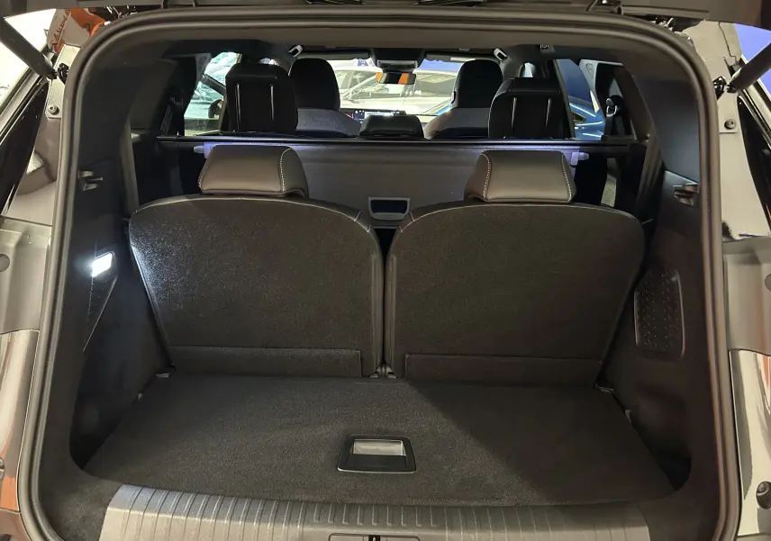 Vue arrière du coffre ouvert du Peugeot 5008 gris titane, montrant les sièges arrière rabattus et l'intérieur spacieux.