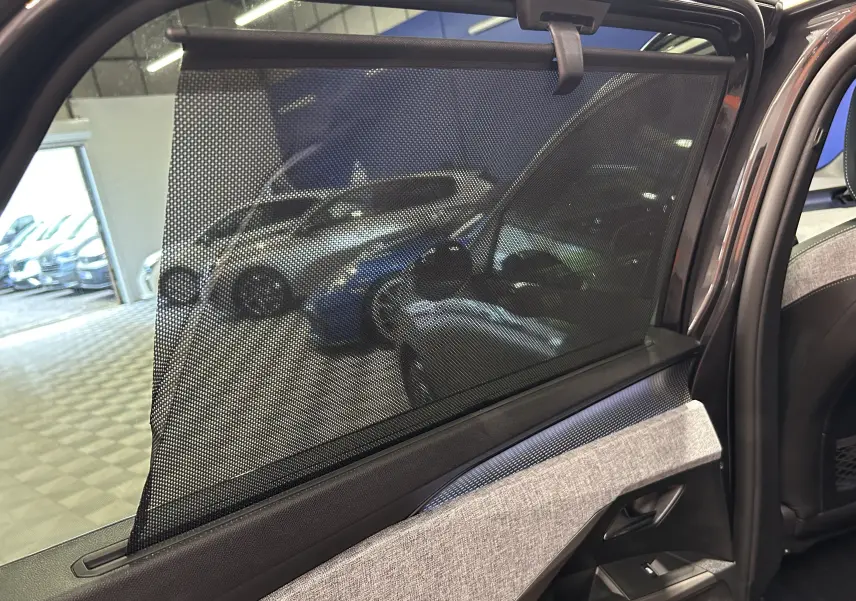 Vue intérieure côté gauche de la porte arrière du Peugeot 5008 gris titane avec pare-soleil en filet déployé.