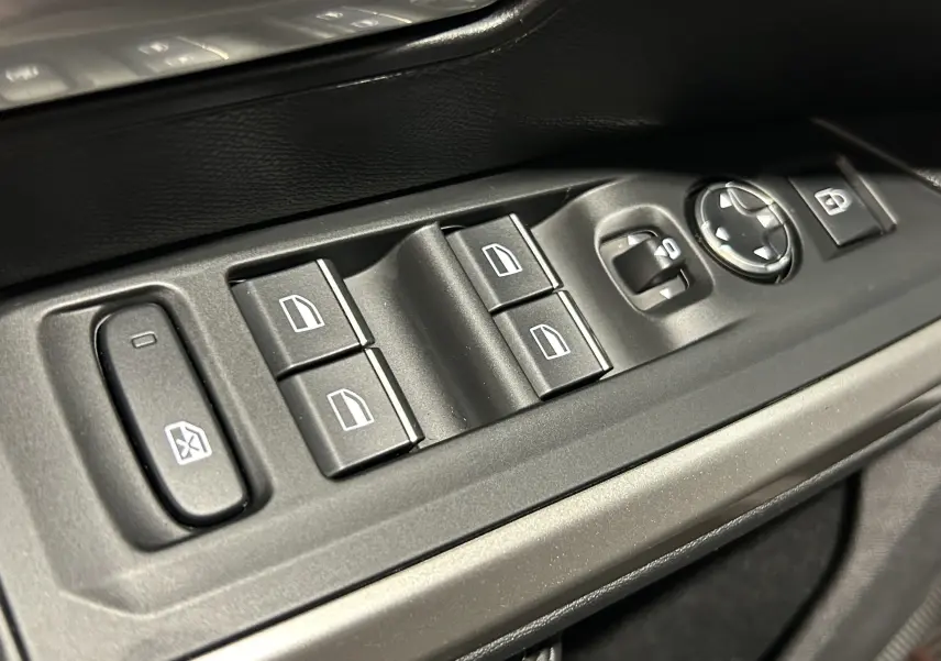 Gros plan sur les commandes électriques des vitres et rétroviseurs côté conducteur du Peugeot 5008 gris titane.