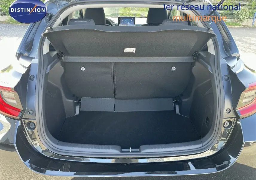 Coffre ouvert en vue arrière d'une Toyota Yaris Hybrid 116ch noir métal, montrant l'espace de chargement vide.