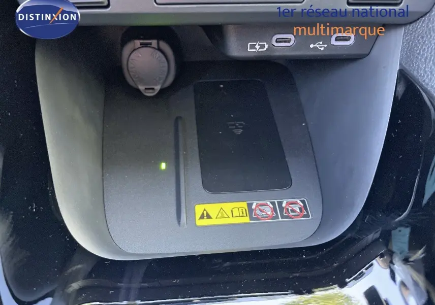 Gros plan sur la console centrale de la Toyota Yaris Hybrid 2025 noire, montrant le chargeur sans fil et ports USB.