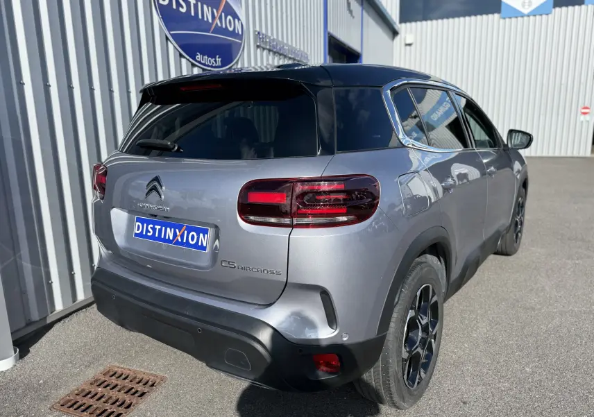 Vue arrière côté droit d'un Citroën C5 Aircross 2024 gris Artense avec toit noir et feux LED distinctifs.