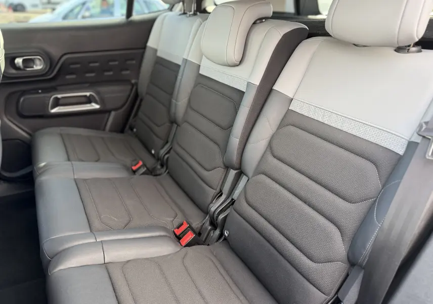 Vue intérieure des sièges arrière en tissu noir et gris du Citroën C5 Aircross 2024, avec appuie-têtes et ceintures visibles.