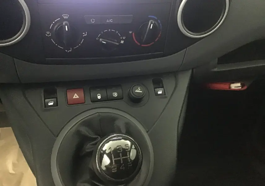 Gros plan sur la console centrale noire du Citroën Berlingo 2018, mettant en valeur le levier de vitesse manuel et les commandes climatiques.