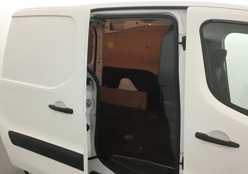 Vue latérale gauche du Citroën Berlingo blanc 2018 avec porte coulissante ouverte montrant l'intérieur boisé du coffre.