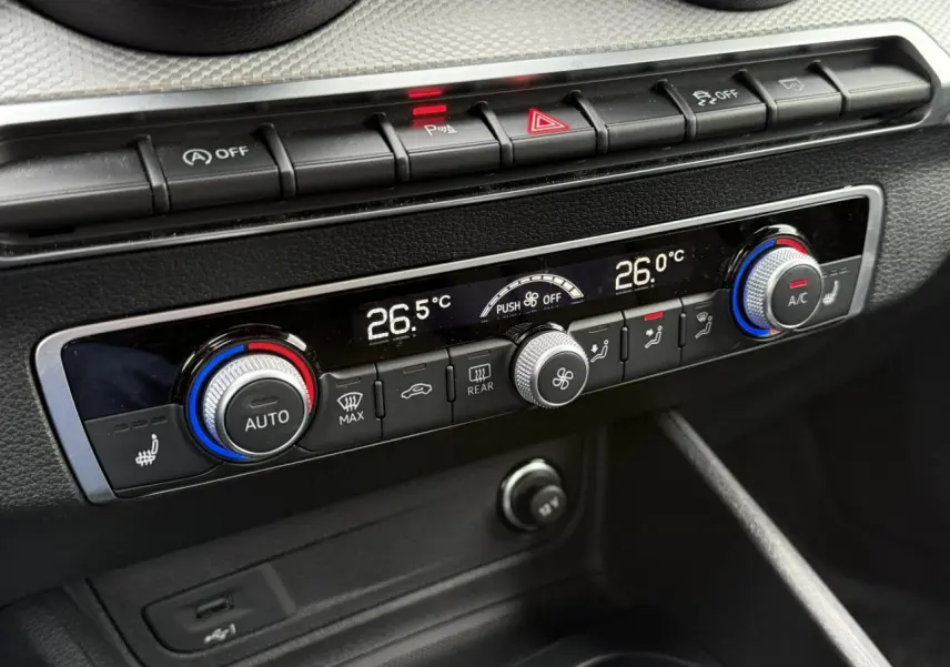 Gros plan sur la console de climatisation de l'Audi Q2 2023, avec réglages numériques et boutons de contrôle noirs.