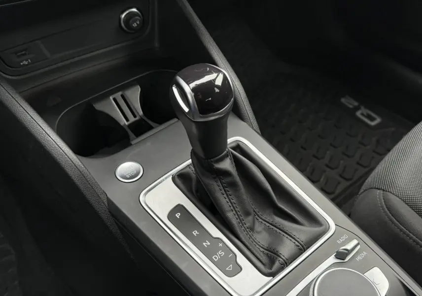 Le levier de vitesse automatique noir et argenté de l'Audi Q2 2023, avec bouton start/stop et console centrale visible.