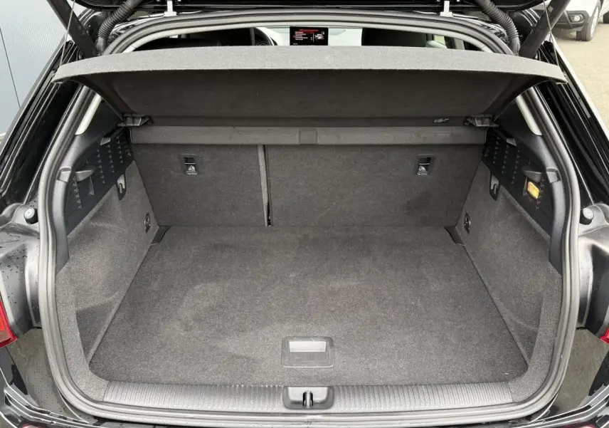 Coffre ouvert vu de face d'un Audi Q2 noir métallisé 2023 avec hayon électrique et intérieur de coffre gris.
