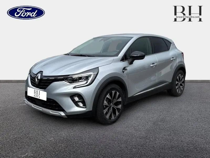 Renault Captur 1.6 E-Tech hybride gris Highland en 3/4 avant droit avec jantes alliage et toit noir.
