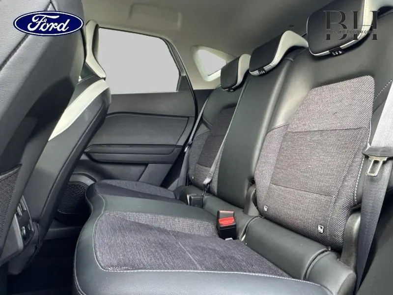 Vue intérieure du côté droit des sièges arrière en tissu gris et cuir noir, avec ceinture de sécurité visible.