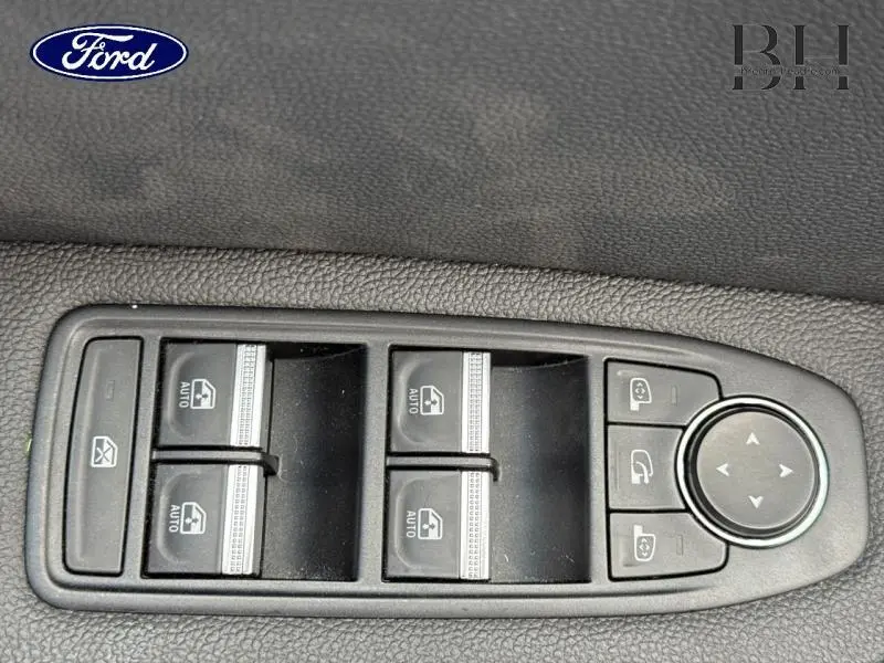 Gros plan sur les commandes de lève-vitres et rétroviseurs électriques sur la porte côté conducteur d'un Renault Captur gris Highland.