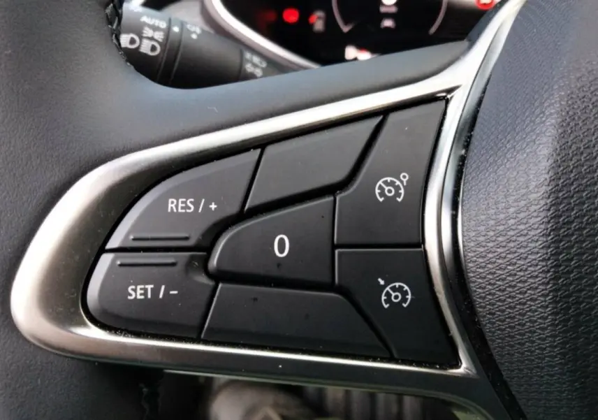 Gros plan sur les commandes du régulateur de vitesse au volant cuir de la Renault Clio V TCE 90 Techno Plus.