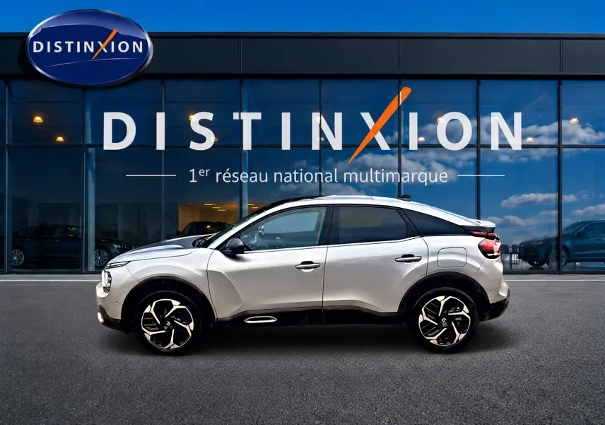 Vue de profil droit d'une Citroën C4 gris clair avec jantes alliage devant une vitrine Distinxion.