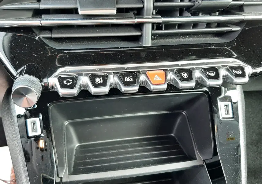 Vue rapprochée de la console centrale du Peugeot 2008 2021, mettant en valeur les commandes de climatisation et les prises USB.