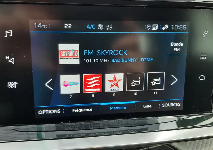 Vue intérieure du tableau de bord du Peugeot 2008 blanc 2021, affichant l'écran multimédia sur la radio FM Skyrock.