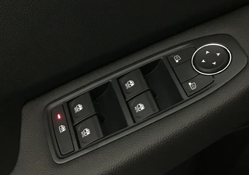 Gros plan sur les commandes de lève-vitres et réglage des rétroviseurs côté conducteur d'une Renault Clio V gris Rafale.