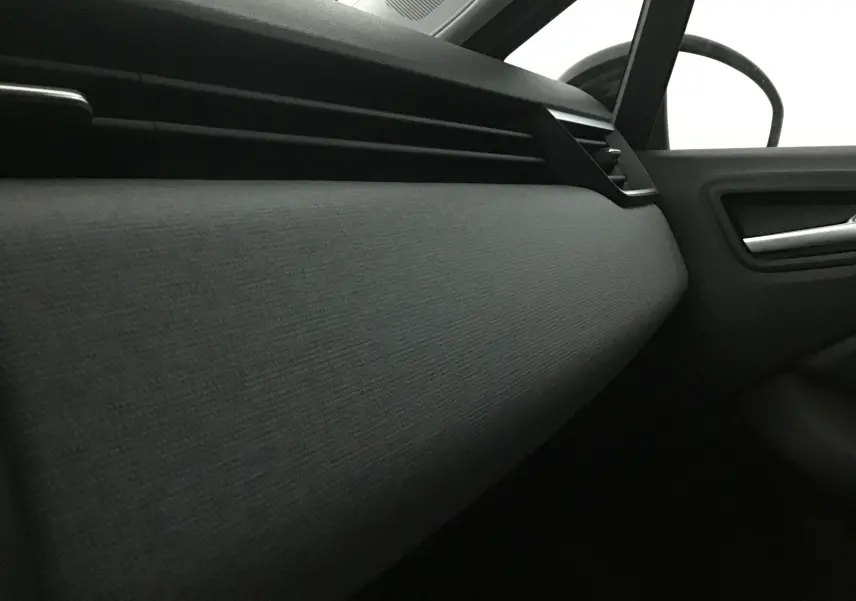 Détail de la garniture intérieure côté passager de la Renault Clio V 1.5 DCI 100 Evolution, avec tissu gris et insert noir mat.