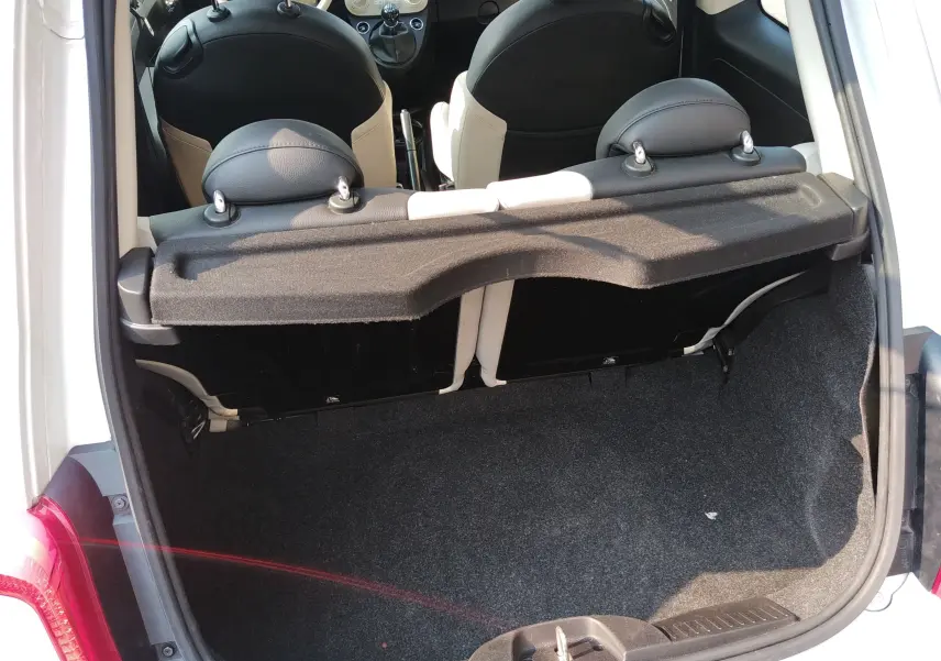 Coffre ouvert vu de l'arrière d'une FIAT 500 blanche, montrant l'intérieur noir et blanc des sièges arrière.