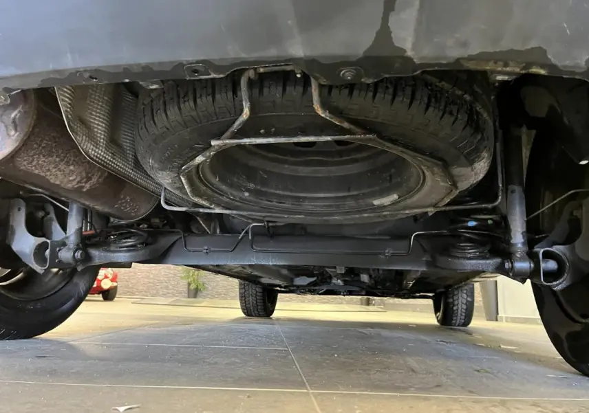 Vue en contre-plongée sous un Dacia Duster noir 2016 montrant la roue de secours fixée sous le véhicule.