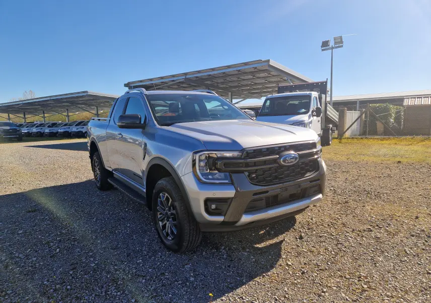 Vue 3/4 avant droite d'un Ford Ranger Super Cabine gris Iconic avec calandre noire et jantes alliage, stationné en extérieur.