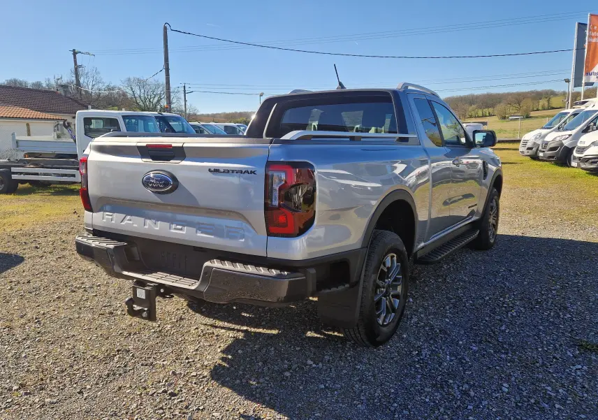 Vue 3/4 arrière droite d'un Ford Ranger Super Cabine gris Iconic avec badge Wildtrak et attelage visible.