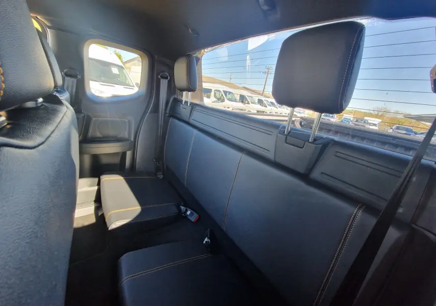 Vue intérieure arrière du Ford Ranger Super Cabine gris Iconic, montrant la banquette en cuir noir avec surpiqûres orange.