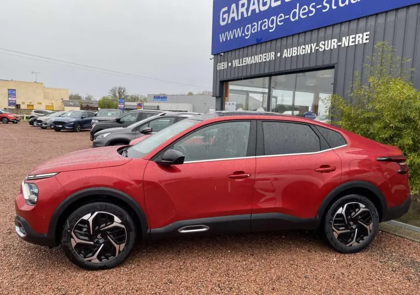 Profil côté gauche d'une Citroën C4 X rouge Elixir 2022 avec jantes alliage et toit ouvrant électrique visible.