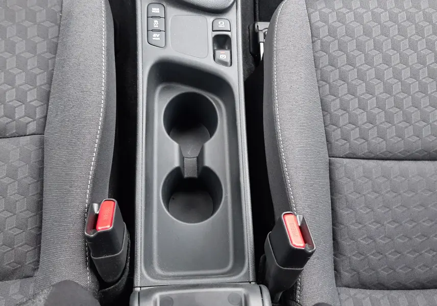 Vue plongeante sur la console centrale noire et les sièges tissu gris foncé de la Toyota Yaris 1.5 Hybrid 2023.