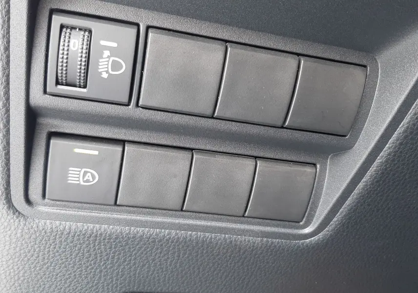 Gros plan sur les commandes d'éclairage et réglage du tableau de bord de la Toyota Yaris blanche 2023.