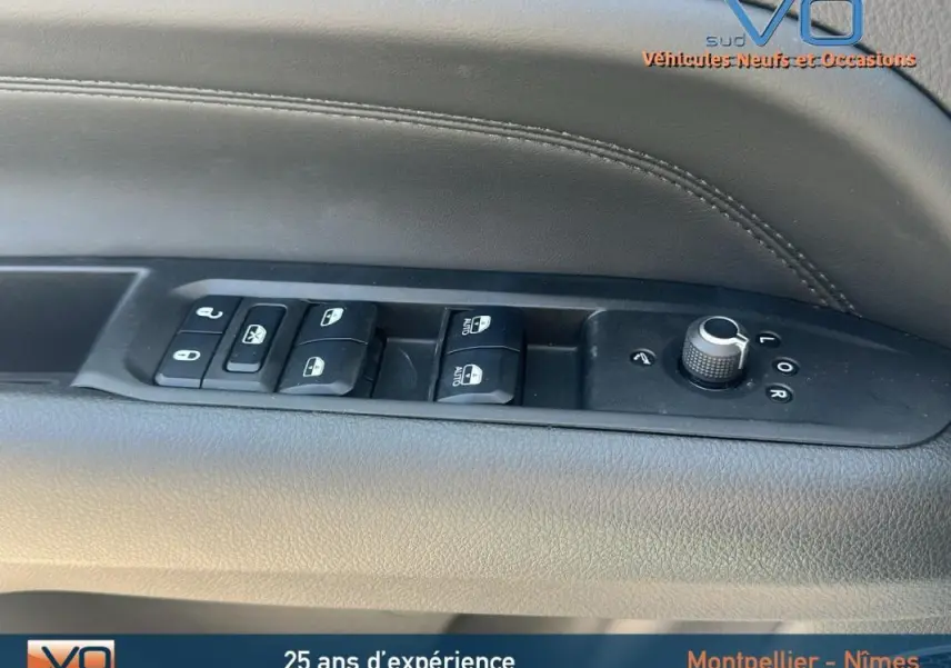 Vue intérieure sur la commande des vitres et rétroviseurs du côté gauche d'un Jeep Compass blanc 2024 avec pack hiver et roue de secours.