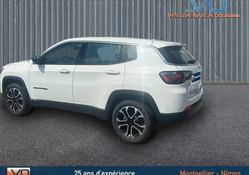 Jeep Compass blanc en vue profil côté gauche, jantes 17 pouces et roue de secours visible à l'arrière.