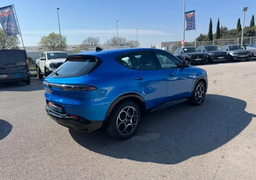 Vue 3/4 arrière droite d'une Alfa Romeo Tonale 2025 bleu foncé avec jantes distinctives à cercles entrelacés.