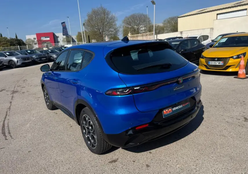 Vue 3/4 arrière droite de l'Alfa Romeo Tonale 2025 bleu foncé avec feux arrière fins et jantes distinctives.