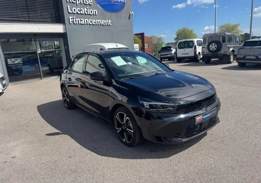 Opel Corsa noire 2025 vue 3/4 avant droit, jantes alliage 16 pouces, stationnée devant un garage.