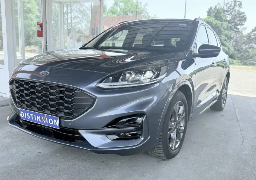 Vue 3/4 avant droit d'un Ford Kuga 2.0 EcoBlue 120 BVA ST-Line X gris métallisé avec calandre noire hexagonale.