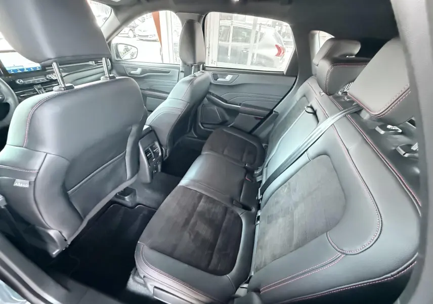 Vue intérieure arrière côté droit du Ford Kuga 2023, sièges cuir noir avec surpiqûres rouges et finitions ST-Line.