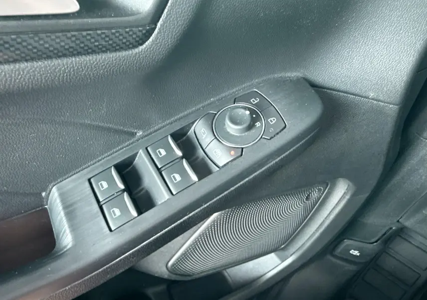 Gros plan sur la commande des vitres et rétroviseurs côté conducteur du Ford Kuga 2023, intérieur noir.